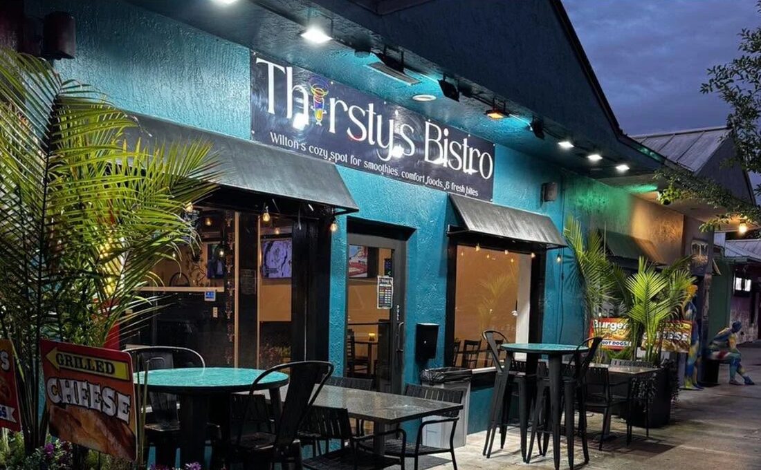 Island City Bistro on Wilton Drive at dusk: the turquoise front, the sign, and the patio tables